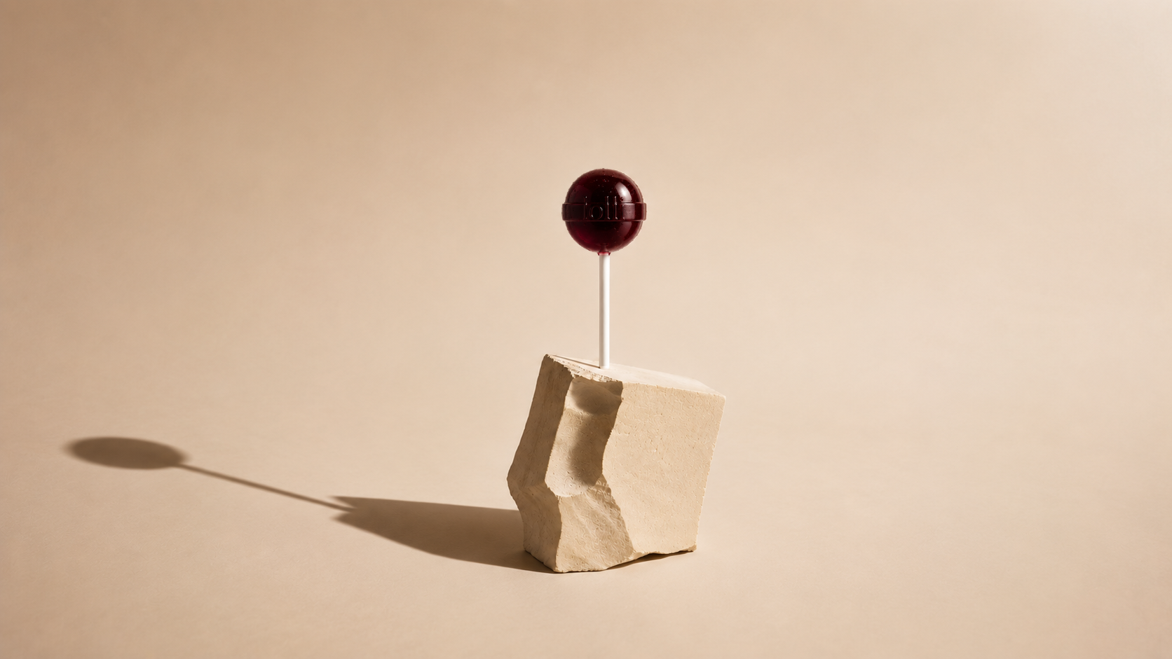 Lolli black cherry fizz lollipop on a stone plinth